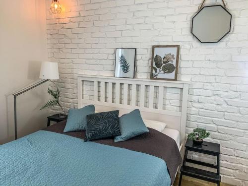 a bedroom with a blue bed and a white brick wall at SOPOT blisko z plaży apartC nr3 in Sopot