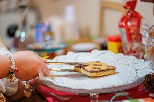 une personne tenant une assiette avec un morceau de gâteau dans l'établissement Bed and Breakfast Dolce Vita Bologna, à Bologne