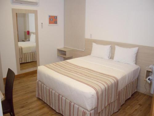 Un dormitorio con una cama grande con sábanas blancas. en Hotel Rede 1, en Campos dos Goytacazes