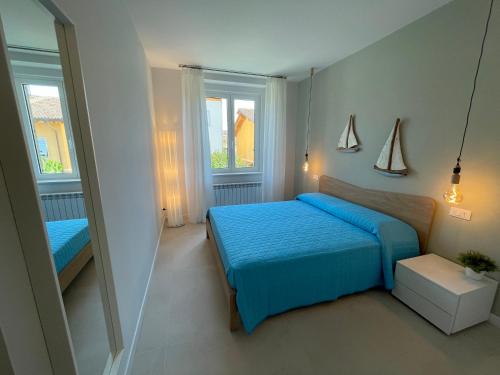 a bedroom with a blue bed and two windows at San Pietro D'orio Verde in Grado