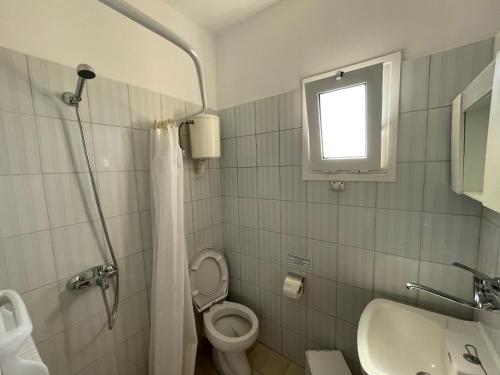 a bathroom with a toilet and a sink and a window at Andreas Studios in Svoronata