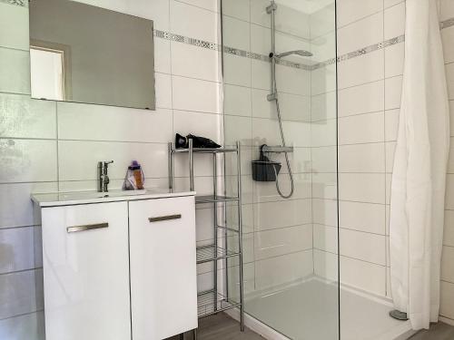 une salle de bain blanche avec une douche et un lavabo dans l'établissement Charmant appartement avec terrasse parking, à Ispagnac