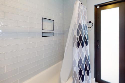 a bathroom with a tub and a shower curtain at Deerfield Divine in Deerfield Beach