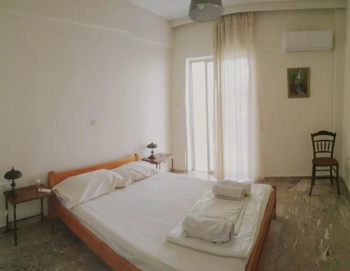 ein Schlafzimmer mit einem großen weißen Bett mit einem Fenster in der Unterkunft Vangelis apartment near Athens Airport in Spáta