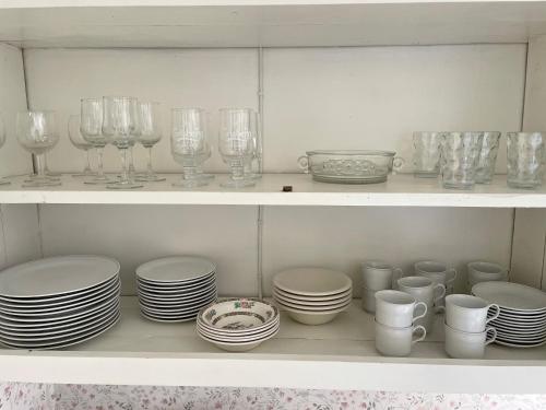 a white shelf filled with plates and cups and glasses at Cottage with beautiful nature, open landscape, forest and lakes in Tingsryd