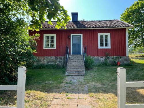 a red house with stairs leading to the door at Cottage with beautiful nature, open landscape, forest and lakes I X I Stuga med fin natur, öppna landskap, skog och sjöar in Tingsryd
