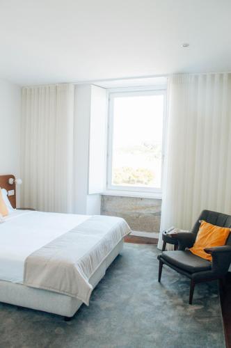 a bedroom with a bed and a chair and a window at Stay In Apartments - D. Hugo 23 in Porto