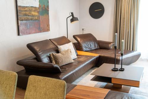 a living room with a leather couch and a table at Meerberg in Pertisau