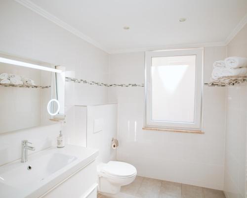a white bathroom with a toilet and a window at Ferienhaus Moselpromenade in Zell an der Mosel