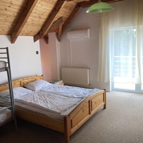 1 dormitorio con cama de madera en una habitación con ventana en Post Apartman, en Balatonmáriafürdő