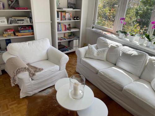 una sala de estar con 2 sofás blancos y una mesa. en KernerApartement en Stuttgart