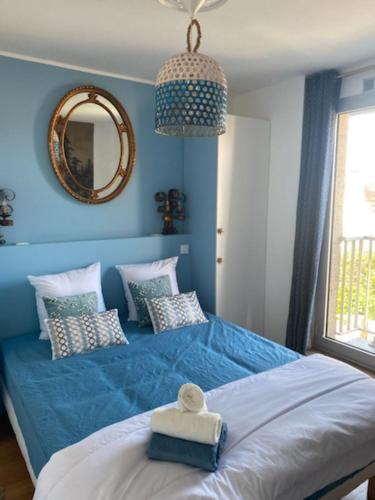 - une chambre bleue avec un grand lit et un miroir dans l'établissement Chez Sylvie, à Perros-Guirec