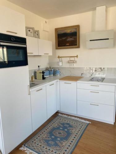 une cuisine avec des armoires blanches et un évier dans l'établissement Chez Sylvie, à Perros-Guirec