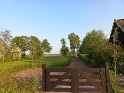 a gate in a field with a dirt road at Lodge De Zandbalk in Sebaldeburen