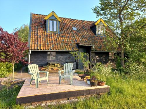 a house with two chairs and a wooden deck at Lodge De Zandbalk in Sebaldeburen