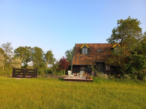 a house with a table and chairs in a field at Lodge De Zandbalk in Sebaldeburen