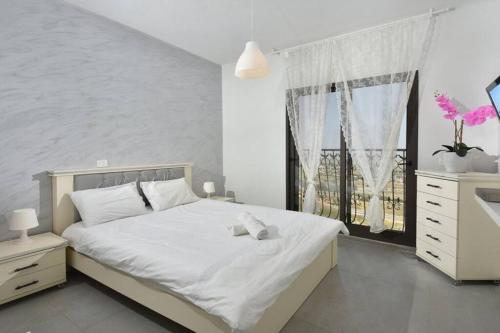 a bedroom with a white bed and a window at לאגו בוטיק - אירוח למשפחות, זוגות עם בריכה פרטית ונוף in Nof Kinneret