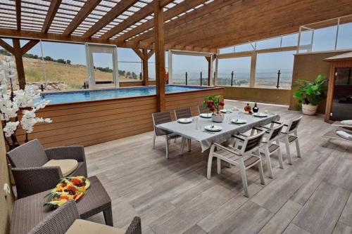 a patio with a table and chairs and a pool at לאגו בוטיק - אירוח למשפחות, זוגות עם בריכה פרטית ונוף in Nof Kinneret