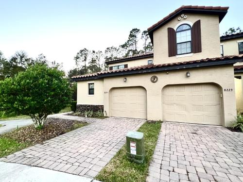 a house with two garage doors and a brick driveway at 8225RB-The Fountains at ChampionsGate townhouse in Kissimmee