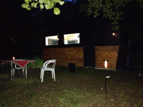 a tiny house with a table in the yard at night at La caravane nature in Saint-Julien-le-Petit