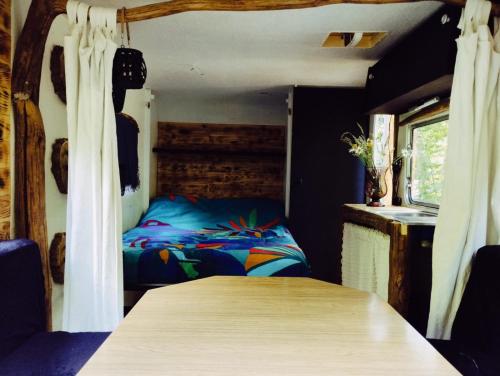 a bedroom with a bed and a table in a room at La caravane nature in Saint-Julien-le-Petit
