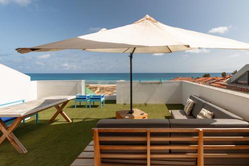 a patio with an umbrella and a table and chairs at New Rooftop Penthouse with Oceanview in Santa Maria