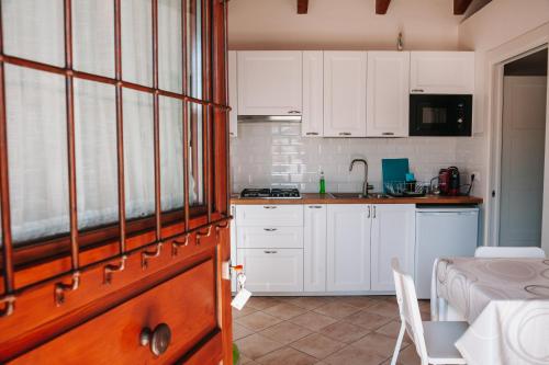 a kitchen with white cabinets and a table and a dining room at Magnolia Rooms in Civitavecchia