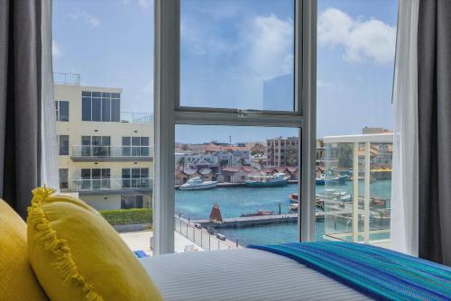een slaapkamer met een raam met uitzicht op een haven bij Magnificent 2 Bedroom Corner Condo With The View in Oranjestad