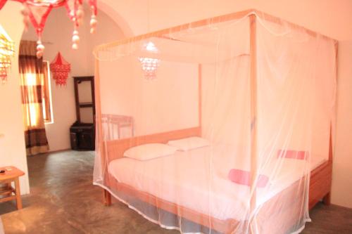 1 dormitorio con 1 cama con dosel en swell surf house, en Arugam Bay