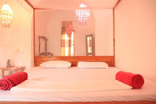1 dormitorio con 1 cama blanca grande con mantas rojas en swell surf house, en Arugam Bay