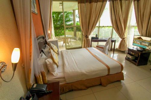 - une chambre avec un lit dans une pièce dotée d'une fenêtre dans l'établissement Dolce Vita Resort Hotel, à Bujumbura