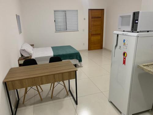 Loft PARIS para Casais, em Iguaba Grande, 150 metros da praia في إيغوابا غراندي: غرفة فيها ثلاجة وطاولة وسرير
