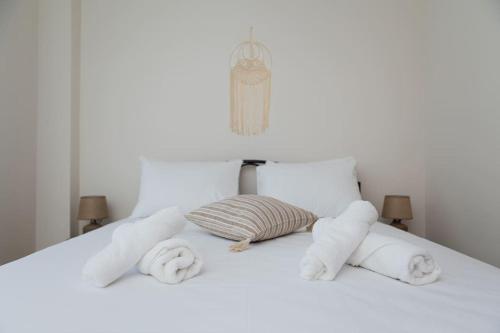 een wit bed met twee rollen handdoeken erop bij Make yourself at home! MYSTH in Nea Fokea