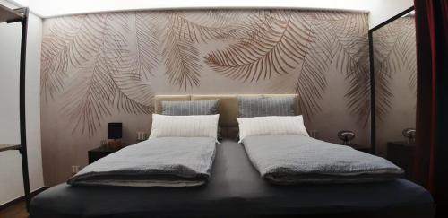 1 dormitorio con 2 camas y una pared con plumas en Vinomare Guesthouse en Fosdinovo