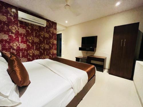 a hotel room with a bed and a television at Hotel Nova Vesu in Surat
