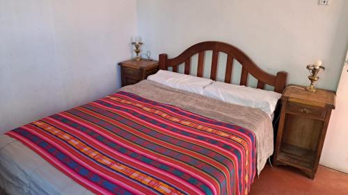 a bedroom with a bed with a colorful blanket on it at Granja Tía Nora in Albardón