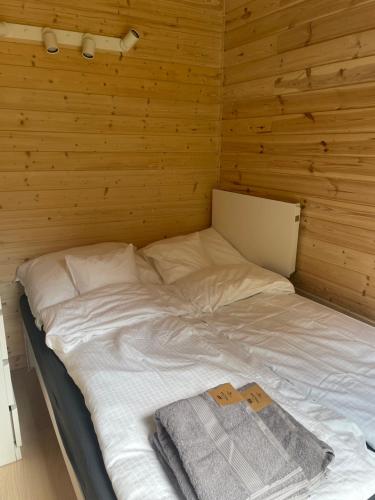 a bed in a room with a wooden wall at Domki Skandynawskie nad Pilicą, Duży Domek 