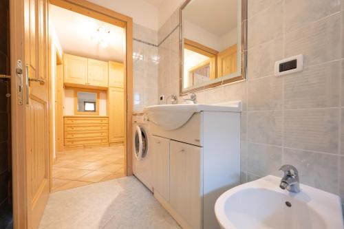 een badkamer met een wasmachine en een wastafel bij Cesa Anna in Campitello di Fassa