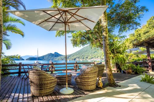 un patio con mesa, sillas y sombrilla en Pousada Cruzoé, en Praia de Araçatiba