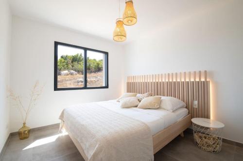 a white bedroom with a bed and a window at Villa-soleil-levant vue mer panoramique in Sari Solenzara