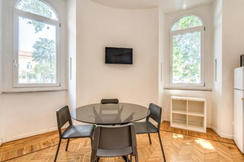 a dining room with a table and chairs and two windows at V E N E R E Apartments in Rome