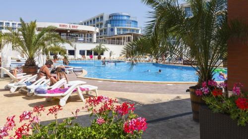 a group of people sitting on lounge chairs in a swimming pool at Design Studio in Atlantis Resort&SPA, Burgas Airport in Burgas City