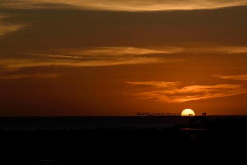 a sunset over the ocean with a pier in the background at MadouBamboo in Ducos