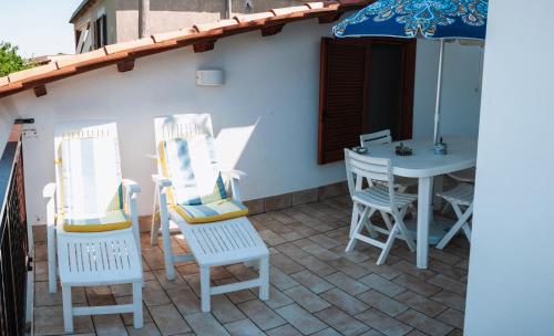 a patio with two chairs and a table with an umbrella at Magnolia Rooms in Civitavecchia