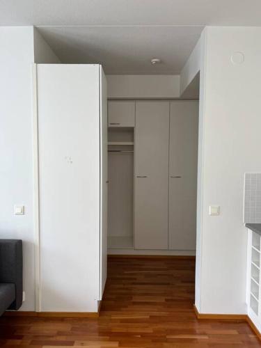 an empty living room with white walls and wood floors at Studio by Sello shopping mall in Espoo