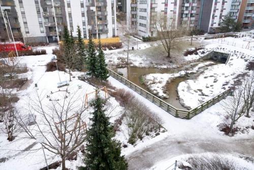 un parque cubierto de nieve frente a un edificio en Studio by Sello shopping mall en Espoo