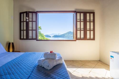 um quarto com uma cama azul e uma janela em Pousada Cruzoé em Praia de Araçatiba