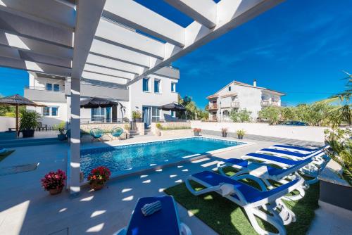 a patio with lounge chairs and a swimming pool at Penthouse apartment Polo in Bibinje