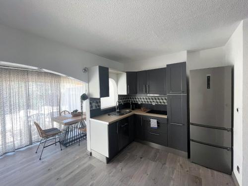 - une cuisine avec des armoires noires et une table dans une pièce dans l'établissement Villa Village Naturiste Karess, au Cap d'Agde