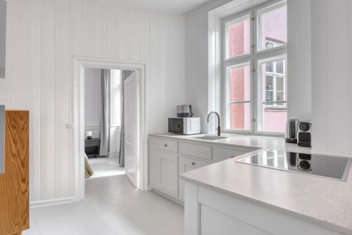 a white kitchen with a sink and a window at Cozy Apartments in Heart of Copenhagen Near Strøget & Højbro Plads in Copenhagen